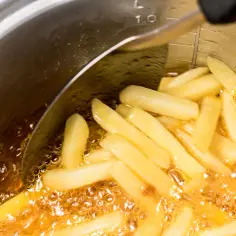 Frytki smażące się w gorącym oleju w garnku.
